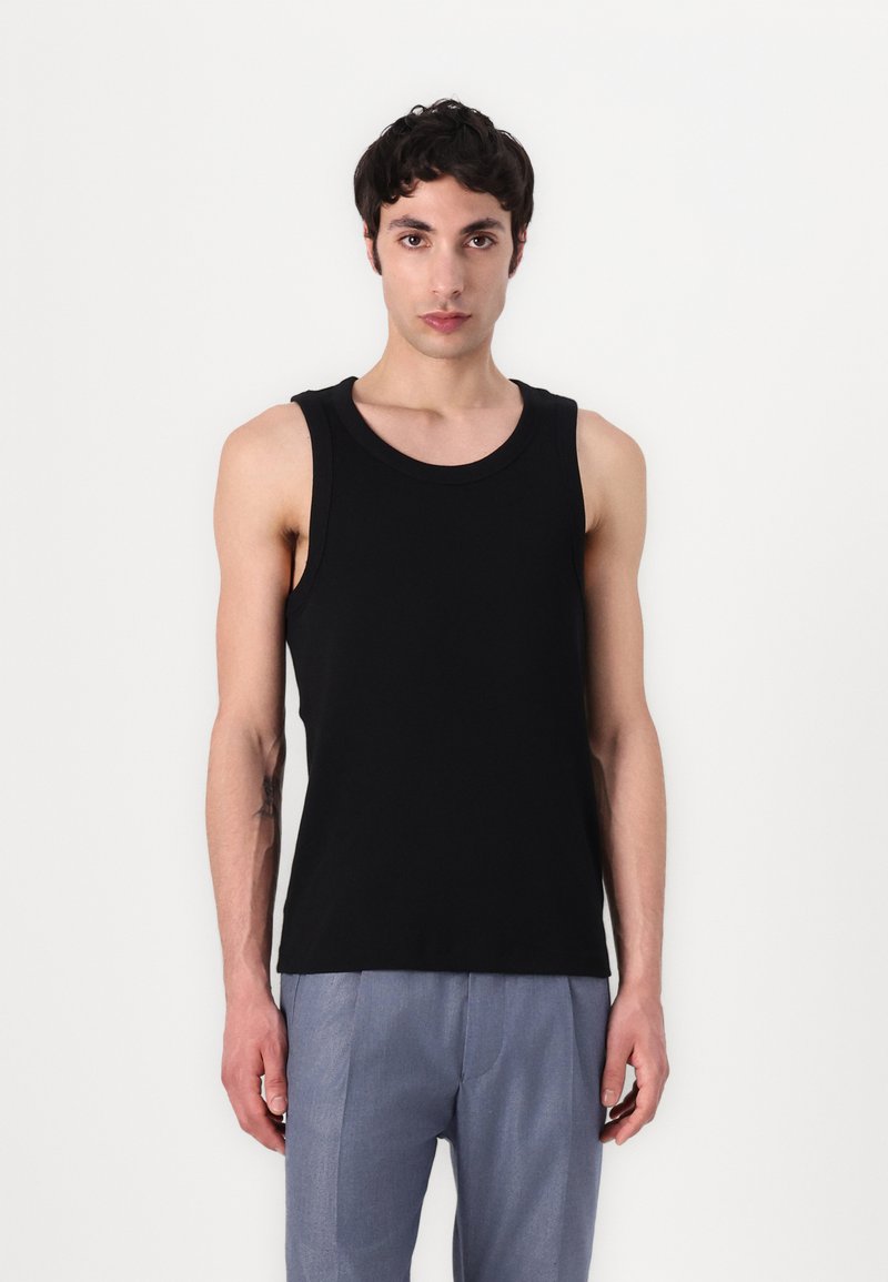 Zwart mouwloos tanktop gemaakt van zachte stof; heeft een ronde halslijn en een aansluitend ontwerp, gecombineerd met lichtgrijze broeken.