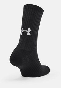 Sorte, ribbede sokker lavet af et blødt materiale med et hvidt Under Armour-logo på siden samt en forstærket hæl og tå for holdbarhed.