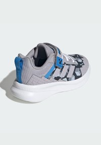 Gray athletic shoe with a textured gray and black patterned upper, blue accents, white laces, and a padded collar. Features a thick white sole.