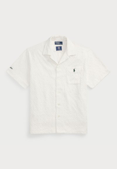 Vit kortärmad skjorta med strukturerat geometriskt mönster, broderad grön logotyp på bröstfickan och öppen krage. Knäppning framtill.