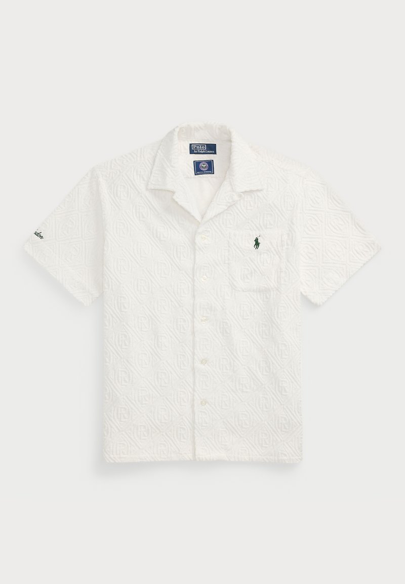 Chemise blanche à manches courtes avec motif géométrique texturé, logo vert brodé sur la poche poitrine et col ouvert. Fermeture bouton à l'avant.