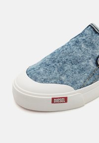 Denim-Sneaker zum Hineinschlüpfen mit weißer Gummisohle, blauer strukturiertem Obermaterial und rotem Diesel-Logoetikett an der Seite.