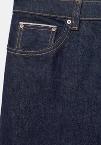 Jean en denim bleu foncé montrant la poche avant, la petite poche à rivets et les détails de couture orange sur la texture du tissu.
