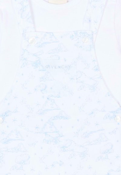 Salopette blanche pour bébé avec des croquis sur le thème de la nature en bleu pâle et "Givenchy" brodé sur la poitrine, attachée par des boutons blancs sur les bretelles.