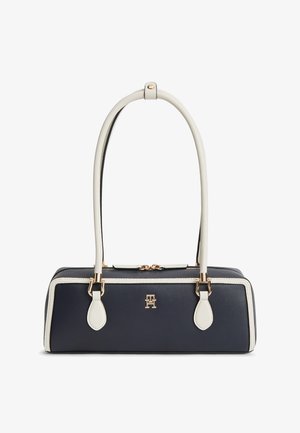 Sac à main rectangulaire bleu marine avec garniture blanche et longues anses blanches, ferrures dorées et logo embossé à l'avant.