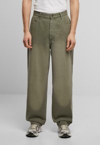 Pantalones de algodón verde de pierna ancha con cierre de botón, cinturilla con trabillas y bolsillos frontales. Textura suave con detalles de costura sutiles.