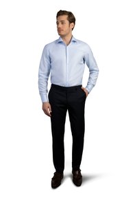 Hellblaues Langarmhemd mit Button-Down-Kragen, kombiniert mit dunklen Stoffhosen und braunen Schuhen. Glattes Material mit taillierter Passform.