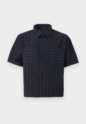 Camisa de manga corta en tela azul marino oscuro con rayas verticales blancas. Cuenta con un cuello clásico y dos bolsillos en el pecho con rayas horizontales.