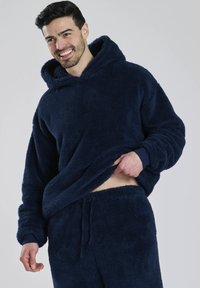 Marineblauer Fleece-Hoodie mit großer Kapuze und Kängurutasche, ausgestattet mit dickem, weichem Material. Kombiniert mit passenden Fleece-Hosen.