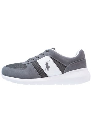 Baskets grises et noires avec semelle blanche et panneau latéral arborant un logo de joueur de polo, design bas et fermeture à lacets.