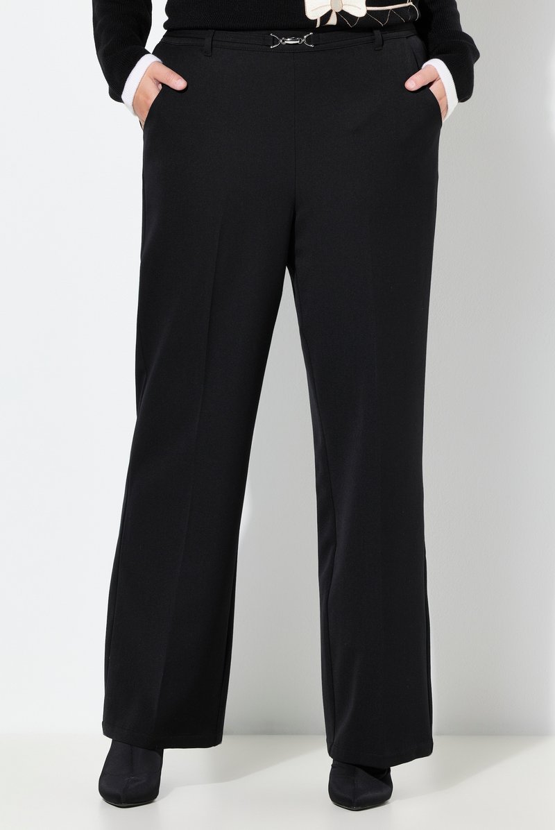Černé široké kalhoty z hladké látky, s předními kapsami a stříbrnou přezkou opasku. Čisté linie a střih na míru.