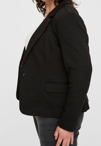 Blazer nero su misura con rever a incavo, chiusura con un solo bottone, due tasche laterali, vestibilità strutturata e tessuto strutturato.