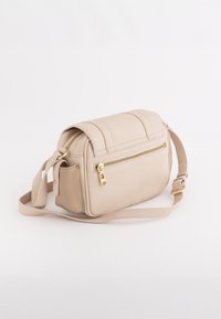 Beige tekstureret crossover-taske med en frontlomme med lynlås, justerbar strop og guld hardware detaljer. Kompakt rektangulær form.
