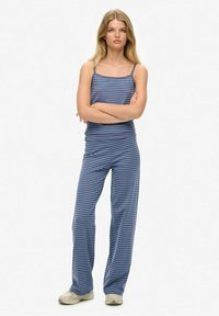 Conjunto de dos piezas a rayas azules con una camiseta ajustada y pantalones de corte holgado. Tela suave, tirantes finos y una silueta cómoda.
