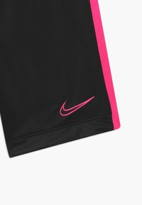 Pantalones cortos deportivos negros con paneles laterales de malla rosa y un logo Nike swoosh rosa. Tela suave con una textura transpirable.
