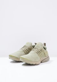 Světle zelené sportovní boty s vrchní částí z síťoviny, strukturovaným povrchem, pružnými tkaničkami a polstrovanou podrážkou. Na jazyku je výrazné logo.