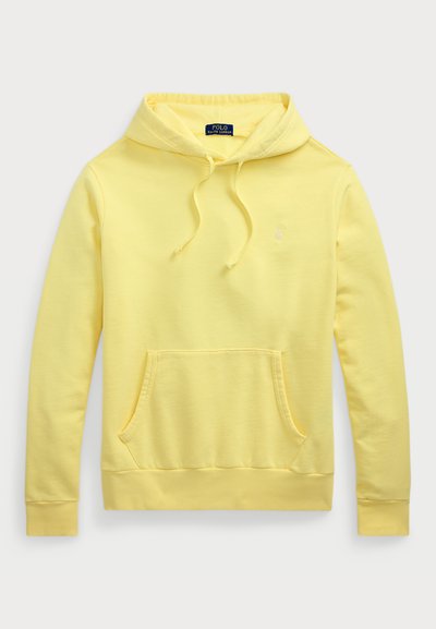 Dzeltena kokvilnas kapucīna džemperis ar priekšējo kangaroo kabatu, aukliņu kapuci un nelielu izšūtu logotipu uz krūts. Gluda tekstūra, ikdienišķs dizains.