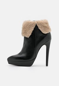 Stivaletto in pelle nera con tacco a stiletto alto, caratterizzato da un morbido colletto in ecopelliccia beige e un design a punta.