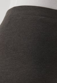 Dark gray elastic fabric with a smooth texture, featuring a fitted design and a wide waistband, suitable for stretch and comfort.