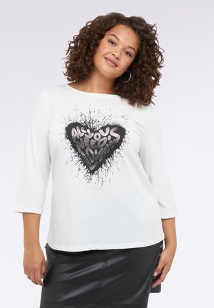 Weißes Langarm-T-Shirt mit einem Rundhalsauschnitt, das in der Mitte ein schwarzes und silbernes Herzgrafik mit Spritzereffekt zeigt.