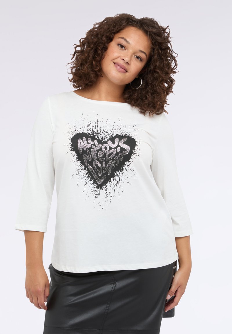 Weißes Langarm-T-Shirt mit einem Rundhalsauschnitt, das in der Mitte ein schwarzes und silbernes Herzgrafik mit Spritzereffekt zeigt.