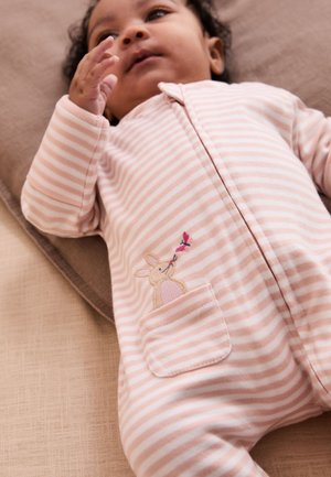 Baby, der ligger ned, iført en lyserød og hvidstribet heldragt med en kanin og en sommerfugl broderet på forlommen.