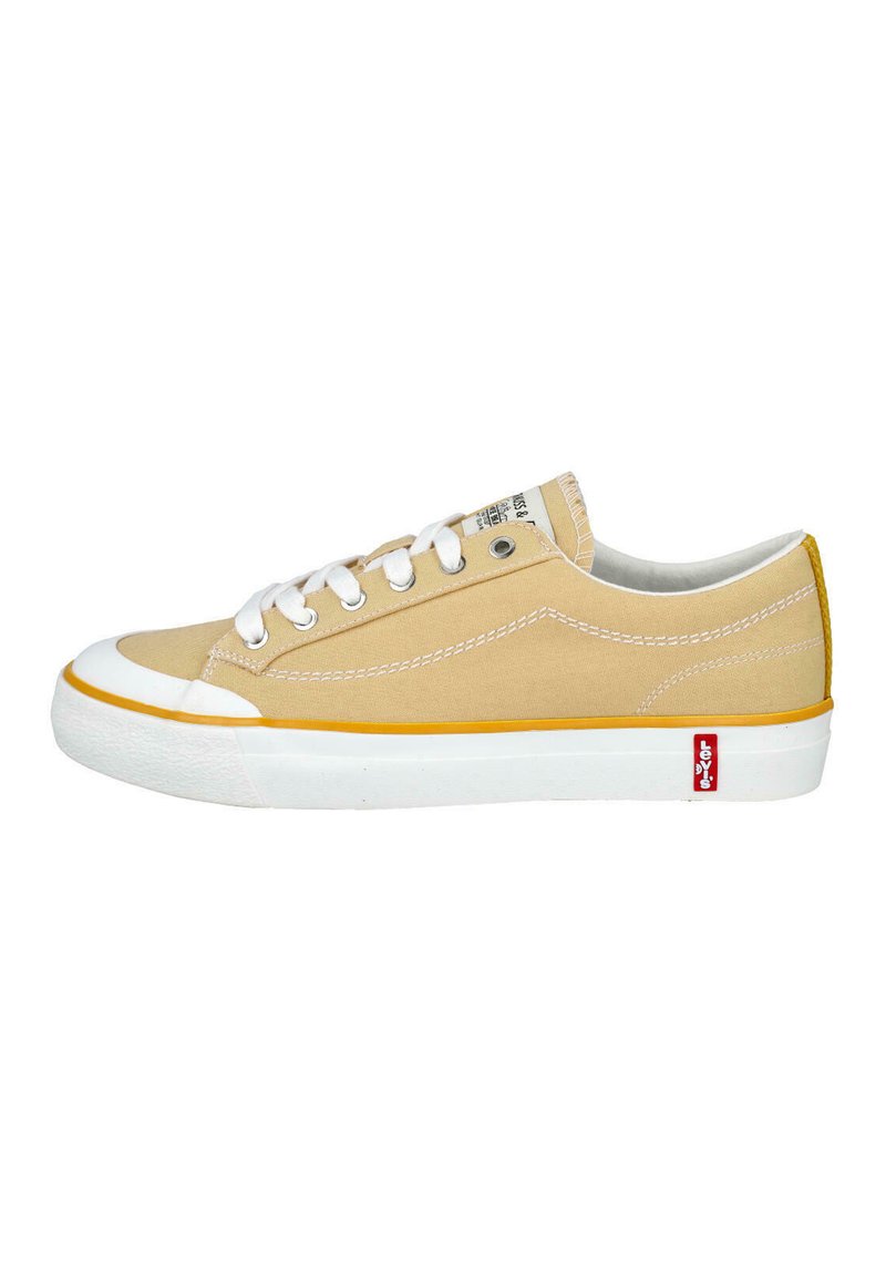 Zapatilla beige de lona baja con suela de goma blanca, cordones blancos, ribete naranja y etiqueta con el logo rojo de Levi’s en el lateral.