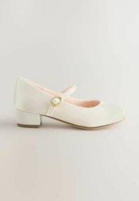 Pantof Mary Jane din material alb, cu vârf rotunjit, toc mic pătrat și o baretă cu o cataramă decorativă aurie. Textură netedă.