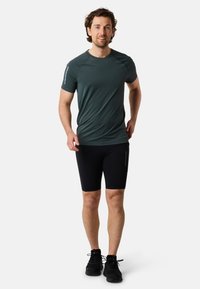 T-shirt de sport gris à manches courtes ; short noir ajusté ; chaussures de sport noires ; design simple sans motifs ni logos visibles.