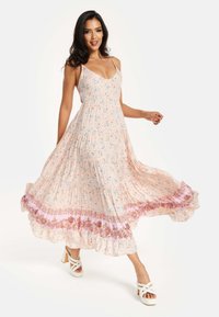 Floral-patterned maxi dress in soft pink with tiered detailing and a ruffled hem. Features thin straps and a fitted bodice.