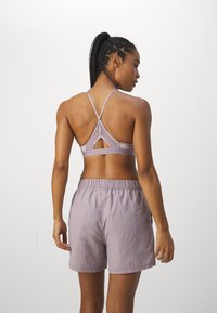 Lila sportbeha met kruislings ontwerp op de achterkant en een sleutelgatdetail, gecombineerd met bijpassende lila shorts met een elastische tailleband.