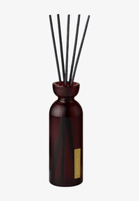 RITUALS reed diffuser in a ribbed dark red glass bottle, featuring five black reed sticks and a gold label.