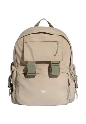 Bež Adidas ruksak s prednjim džepom s preklopom, dva zelena kopčana zatvarača, bočnim džepovima i pletenim privjescima na patentnim zatvaračima.