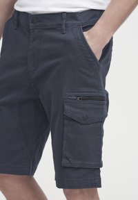 Navy Cargo-Shorts aus Baumwollmischung, mit einer Reißverschlusstasche vorne, einer Seitentasche mit Klappe und gesteppten Details an den Beinen.