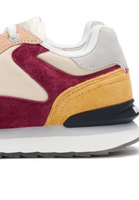 Sneaker met suède en meshpanelen in beige, bordeaux, geel en grijs. Heeft een witte tussenzool en een zwarte buitenzool met textuuraccenten.