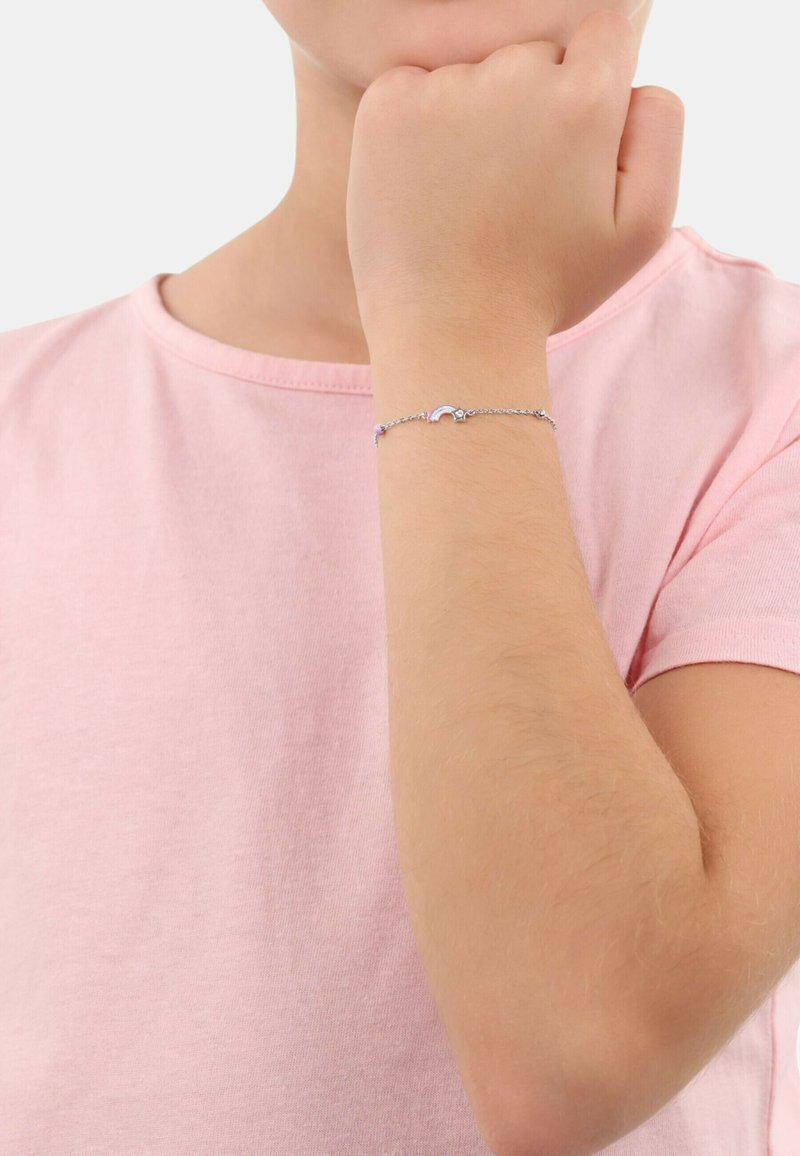 Silberne Armbanduhr mit einem Regenbogendesign und lila Akzenten, am Handgelenk vor einem hellrosa Hemd-Hintergrund getragen.
