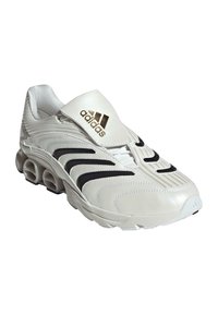 Balti un melni Adidas sporta apavi ar unikālu ventilētu zoles dizainu un polsterētu apkakli, uz kura priekšējā flapa ir Adidas logo.