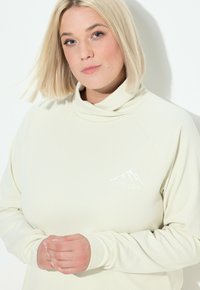 Hellbeige, geripptes Pullover mit hohem Kragen und weißem Berglogo auf der Brust. Verfügt über lange Ärmel und einen lässigen Schnitt.