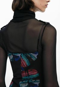 Top nero trasparente con collo alto, caratterizzato da un motivo astratto colorato sul retro. I dettagli includono spalline sottili e spalle strutturate.