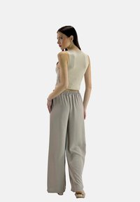 Lichtbeige mouwloze crop top en losse grijze wijde broek met een elastische tailleband. Zachte textuur, minimalistisch ontwerp en geen zichtbare patronen.