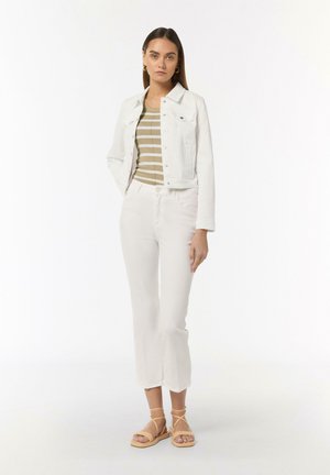 White denim jacket, striped beige and olive tank, white pants with flared hem, and tan strappy sandals, featuring simple hardware and clean lines.