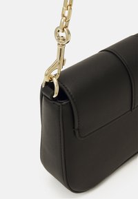 Sac à main en cuir noir à forme structurée, équipé de ferrures dorées et d'une bandoulière en chaîne. Il possède une fermeture à rabat et des détails de couture apparents.