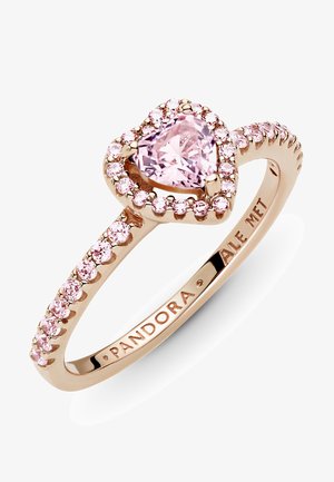 Anello in oro rosa con una pietra rosa a forma di cuore al centro, circondata da piccole pietre rosa lungo la fascia. Dettagli in marcastite.