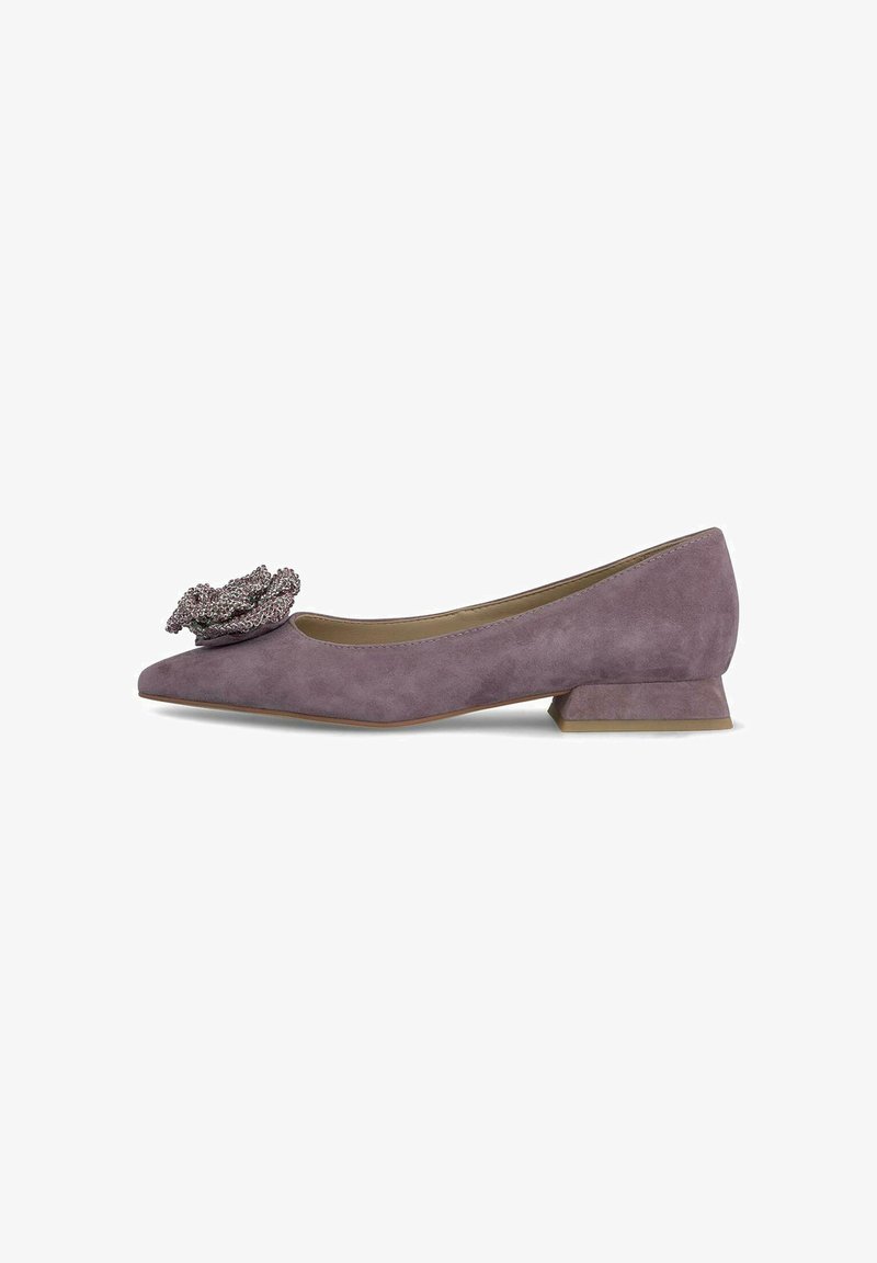 Zapato plano de ante morado con punta afilada, que presenta un acento decorativo de flor y un tacón cuadrado bajo. Textura suave en toda su superficie.