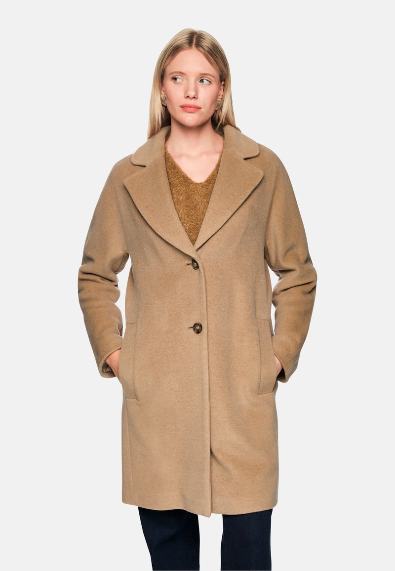 Beige Wollmantel mit Reverskragen, vorderer Knopfleiste und seitlichen Taschen. Weiche Textur und knielanges Design.