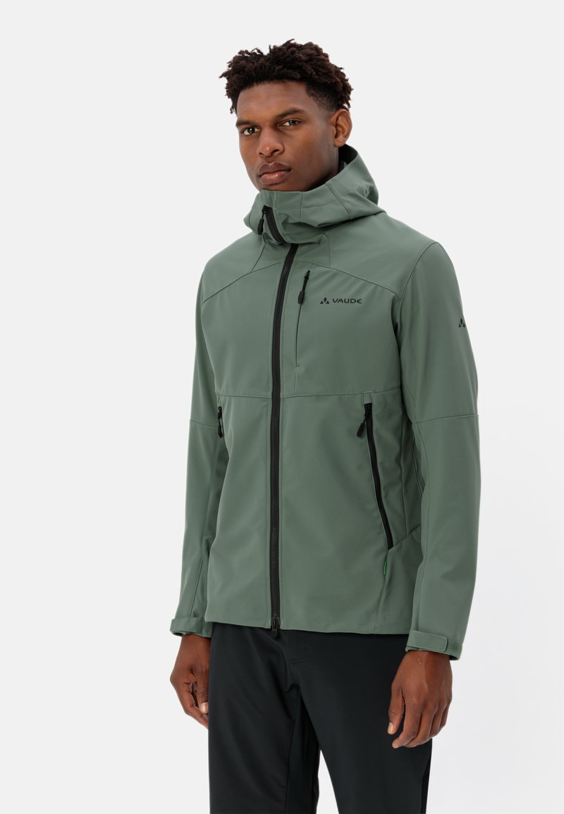 Grüne wasserdichte Softshell-Jacke mit hohem Kragen, Reißverschlusstaschen und sichtbar auf der Schulter platziertem Logo. Glatte Textur mit tailliertem Design.