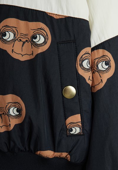 Μαύρο μπουφάν bomber με παιχνιδιάρικα prints που απεικονίζουν καφέ εξωγήινες φιγούρες, μ�ε χρυσό κουμπί σούστα μπροστά και υφή υφάσματος με ματ φινίρισμα.