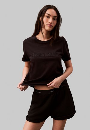 Zwarte katoenen t-shirt met geborduurd "Calvin Klein" logo, gecombineerd met zwarte shorts met logo tailleband, ontspannen pasvorm.