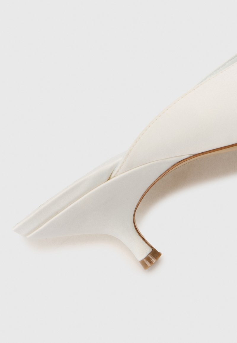 Décolleté in satin bianco con punta affilata e forma modestamente curva, dotato di tacco stiletto sottile e una base marrone a contrasto.