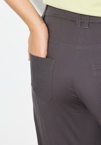 Pantaloni grigi scuri con una texture liscia, caratterizzati da una tasca laterale visibile e cuciture a contrasto lungo le cuciture.